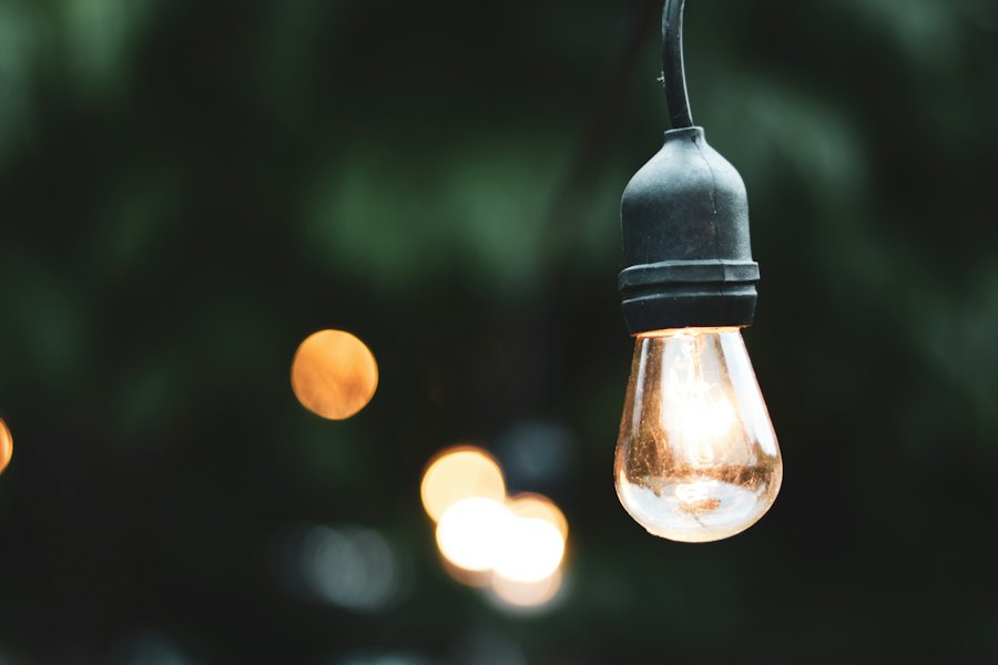 A glowing string light bulb outdoors in the evening