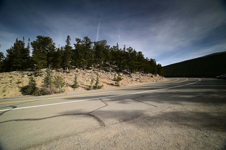A curving mountain road past pine trees and rocky slopes